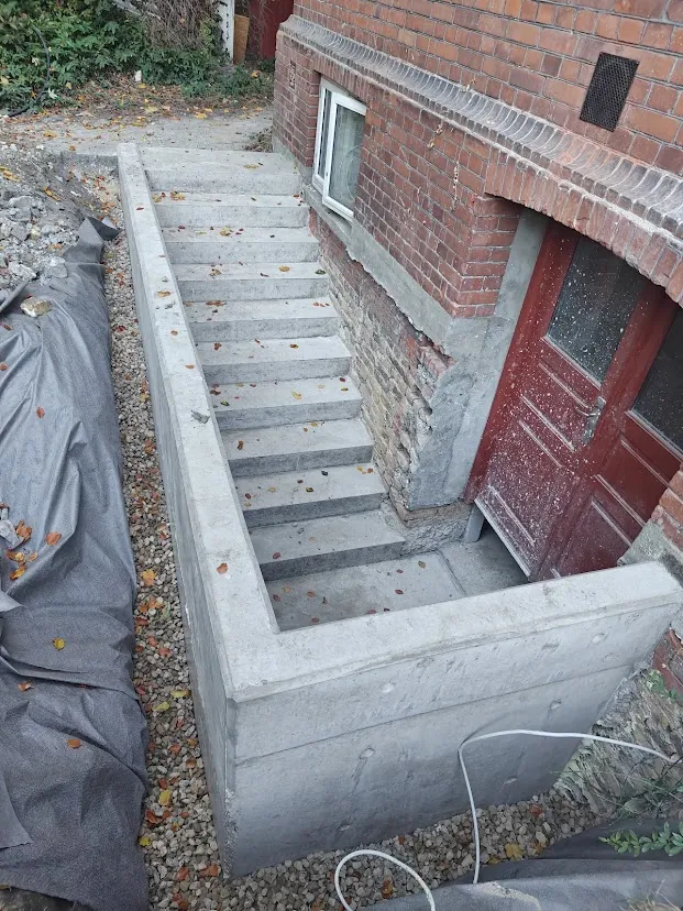 Støbt kældertrappe med støttevæg ved murstenshus
